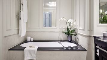 A modern bathroom with a freestanding bathtub, a potted orchid, and a towel rack.