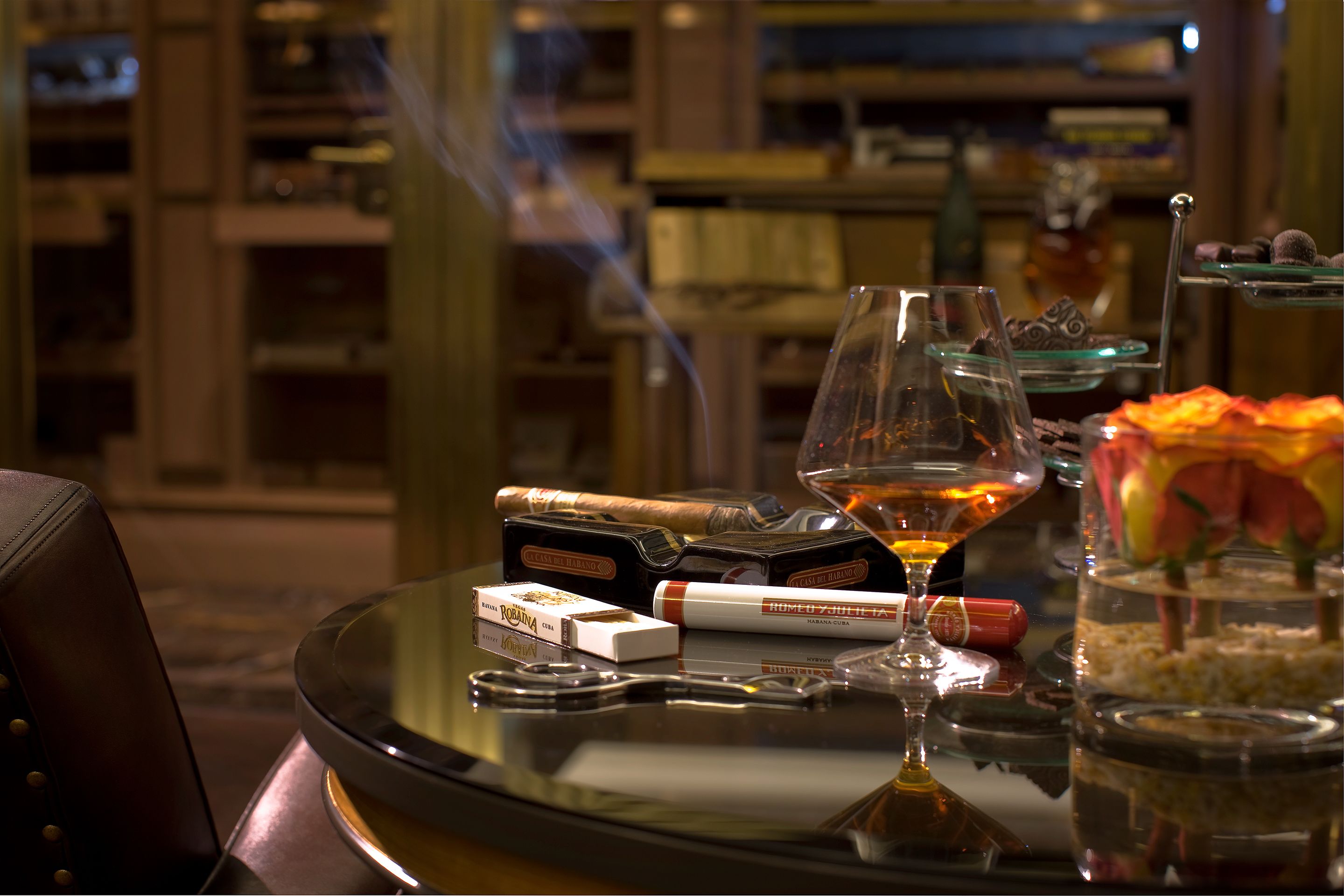 Ein Tisch mit einem Glas, einer Zigarre und einem Whiskeyglas.