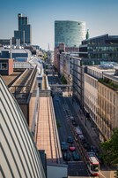 Paesaggio urbano con edifici moderni, un tram e cielo sereno.