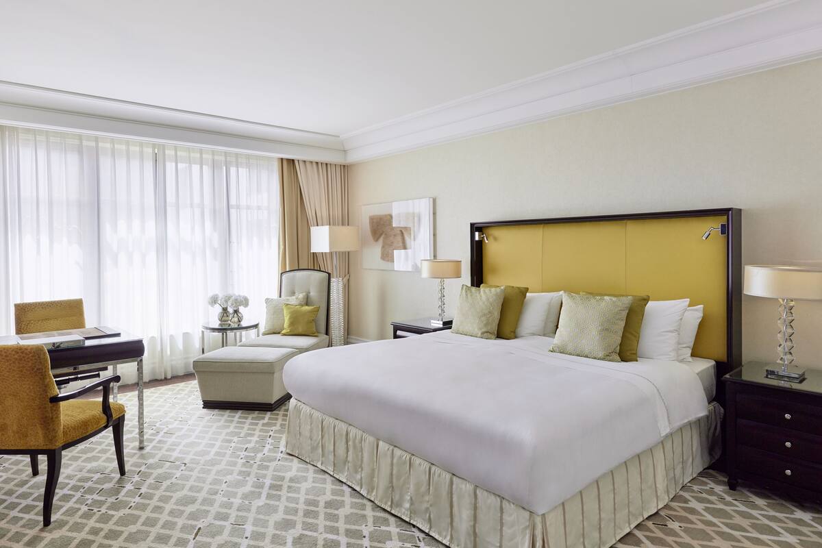 Habitación de hotel con una cama grande, un escritorio, una silla y una mesita de noche con lámparas.