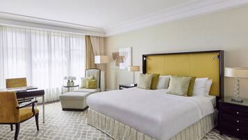 Habitación de hotel con una cama grande, un escritorio, una silla y una mesita de noche con lámparas.