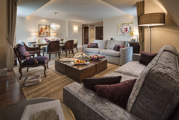 A modern living room with a sofa, armchairs, a coffee table, and a dining area with chairs and a table. - Breidenbacher Hof (Düsseldorf)