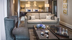 Una habitación de hotel moderna con sofá, sillón y una mesa de centro con objetos decorativos.