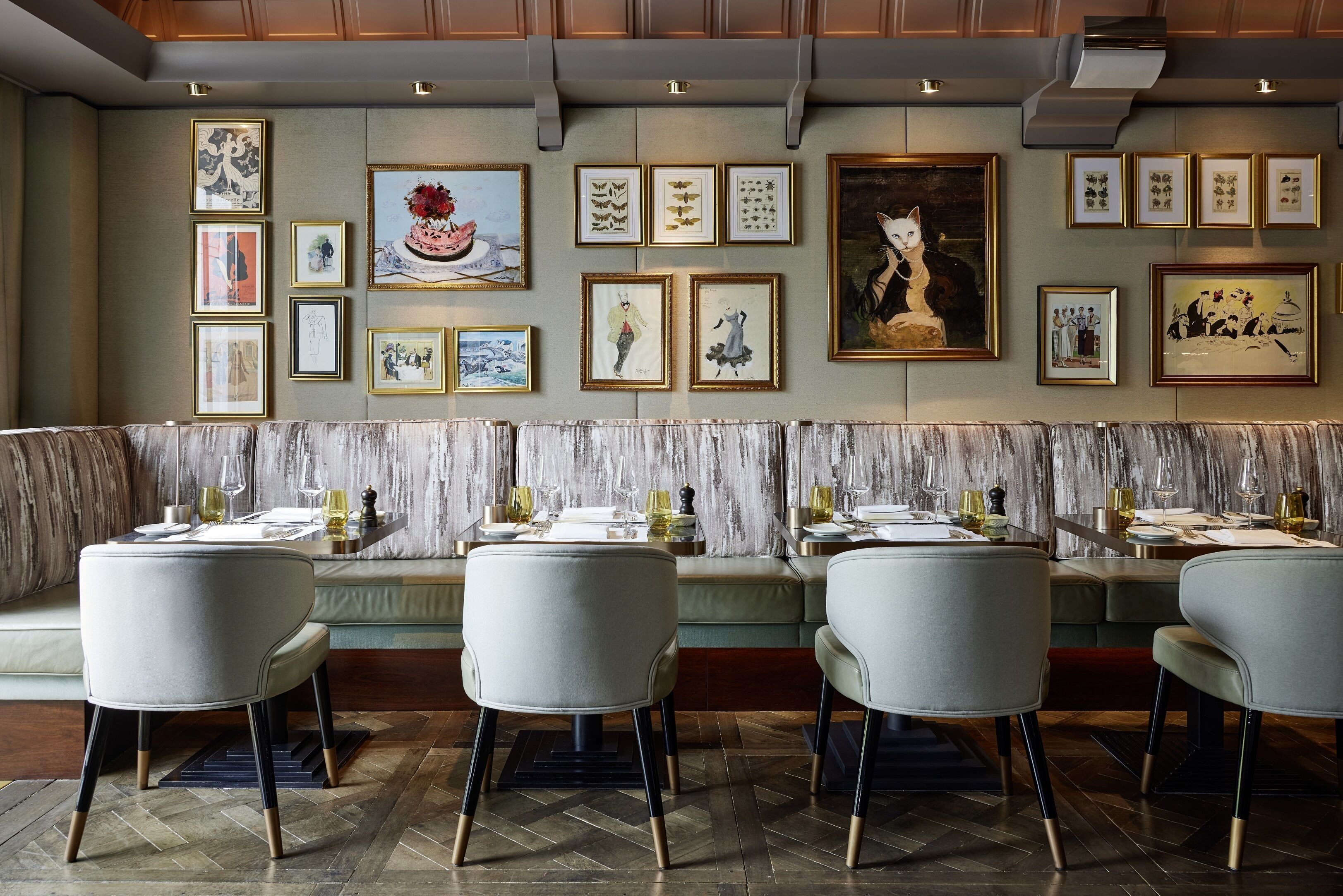 A restaurant with a long bench seating area, framed artwork on the wall, and a modern interior design.