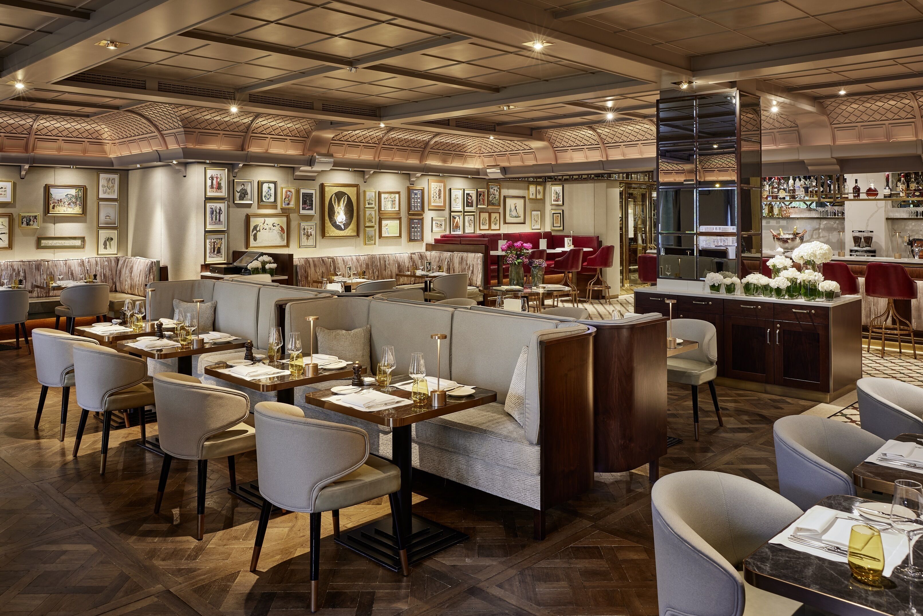 Un ristorante con soffitto alto, pavimento in legno e un'area bar con esposizione di bottiglie.
