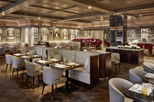 Un ristorante con soffitto alto, pavimento in legno e un'area bar con esposizione di bottiglie.