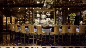 Un bar con piso de mármol, taburetes y una amplia variedad de licores.