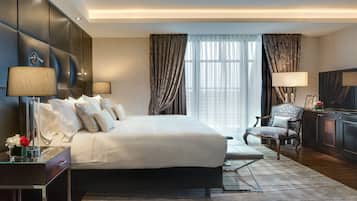 Habitación de hotel moderna con una cama grande, un escritorio con lámpara, una silla y un televisor.
