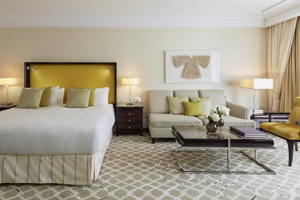 Habitación de hotel con una cama grande, un sofá, una mesa de centro y un escritorio con lámparas.