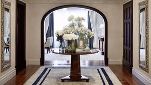 Un amplio pasillo con una mesa redonda de madera, flores blancas y un candelabro.