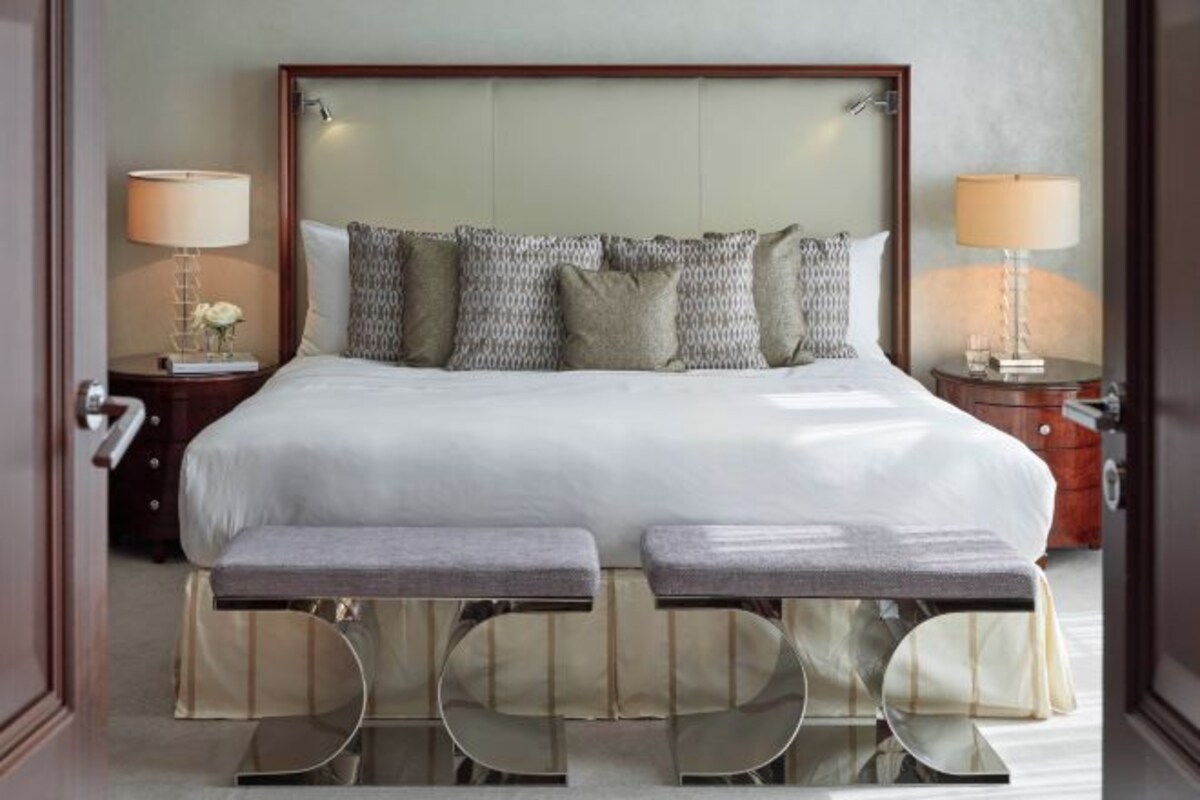Habitación de hotel con una cama grande, dos mesitas de noche, un banco y una mesita de noche con lámparas.