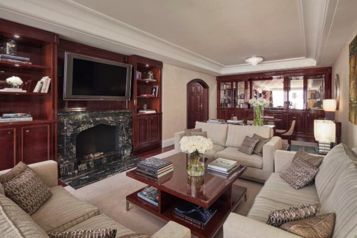 Un salón espacioso con chimenea, asientos cómodos, un televisor y una estantería.
