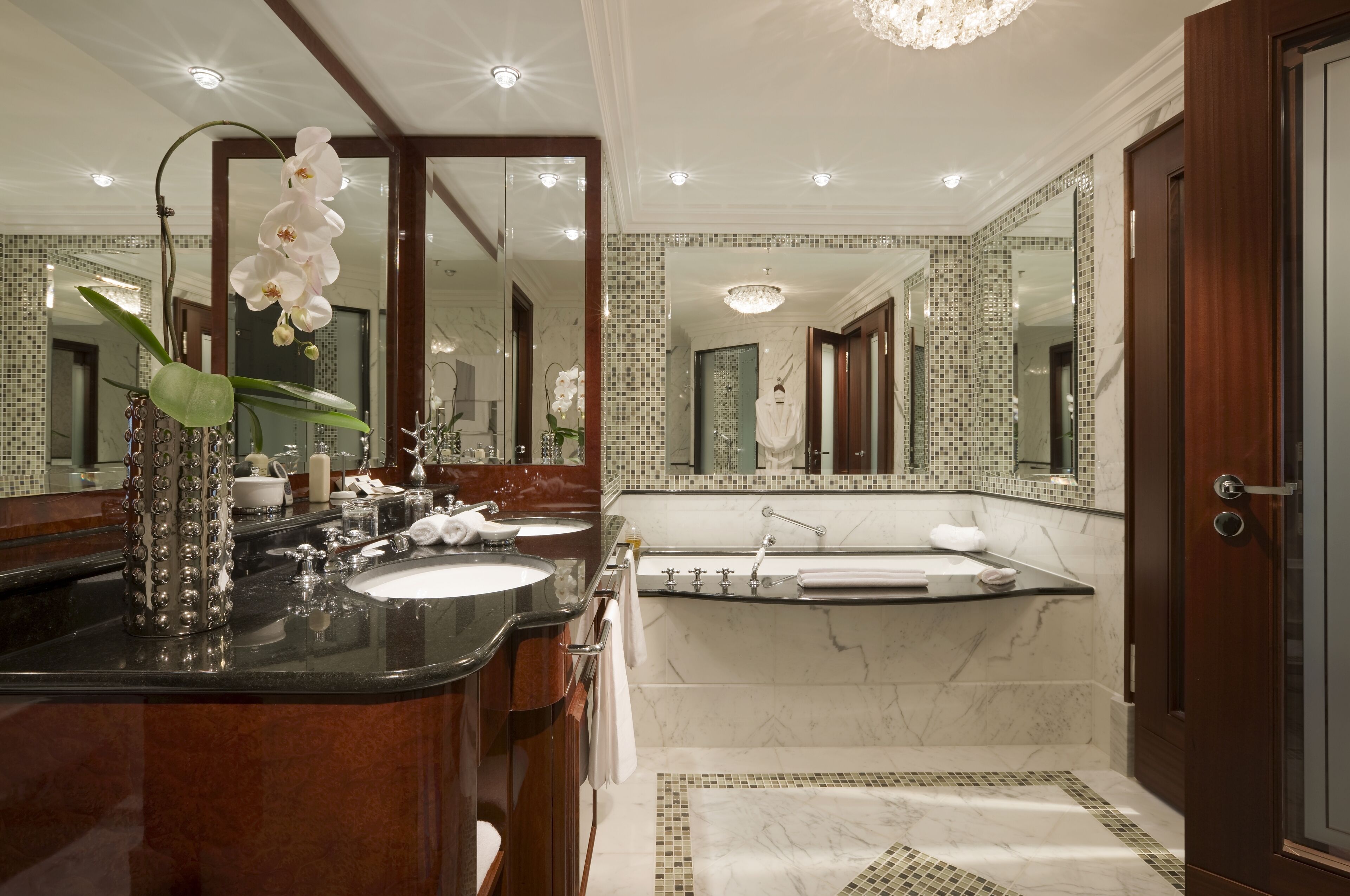 Un baño lujoso con lavamanos de mármol, un espejo grande y una bañera.
