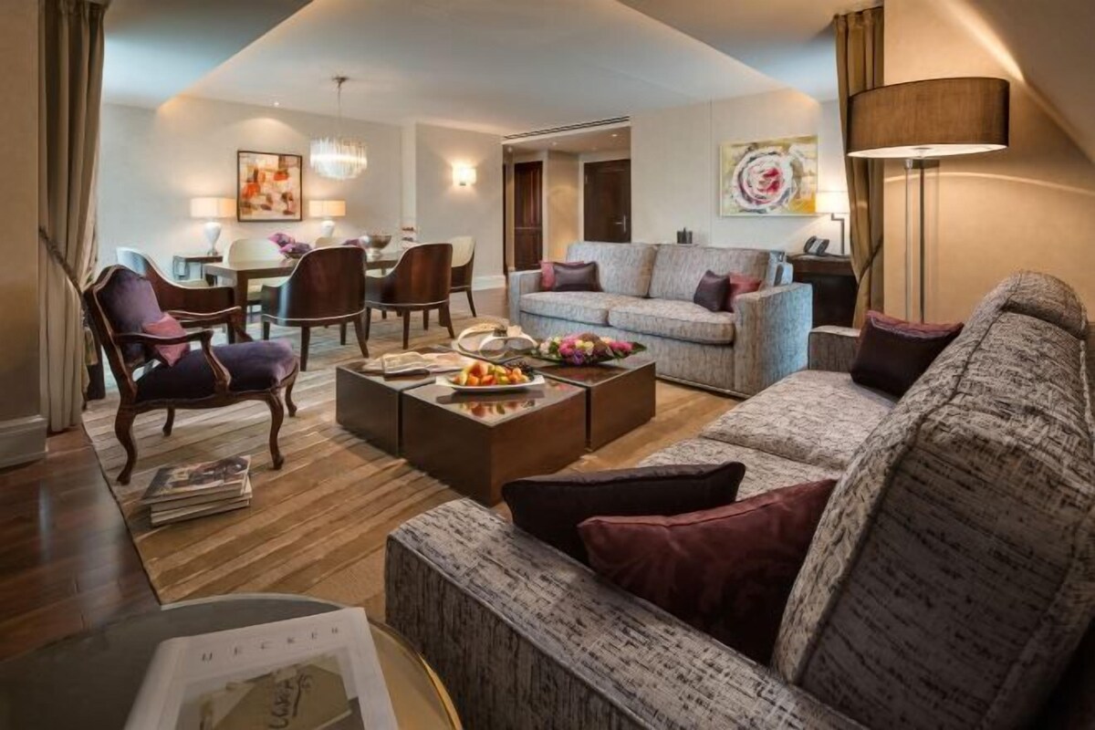 A modern living room with a sofa, armchairs, a coffee table, and a dining area with chairs and a table.