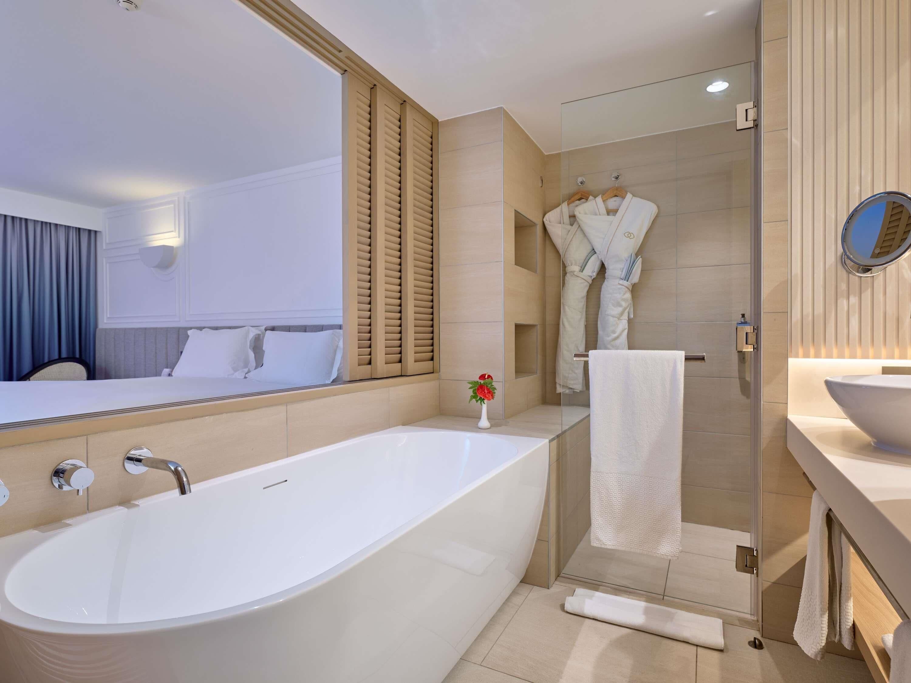 A modern bathroom with a large bathtub, a glass shower enclosure, and a vanity with a mirror.