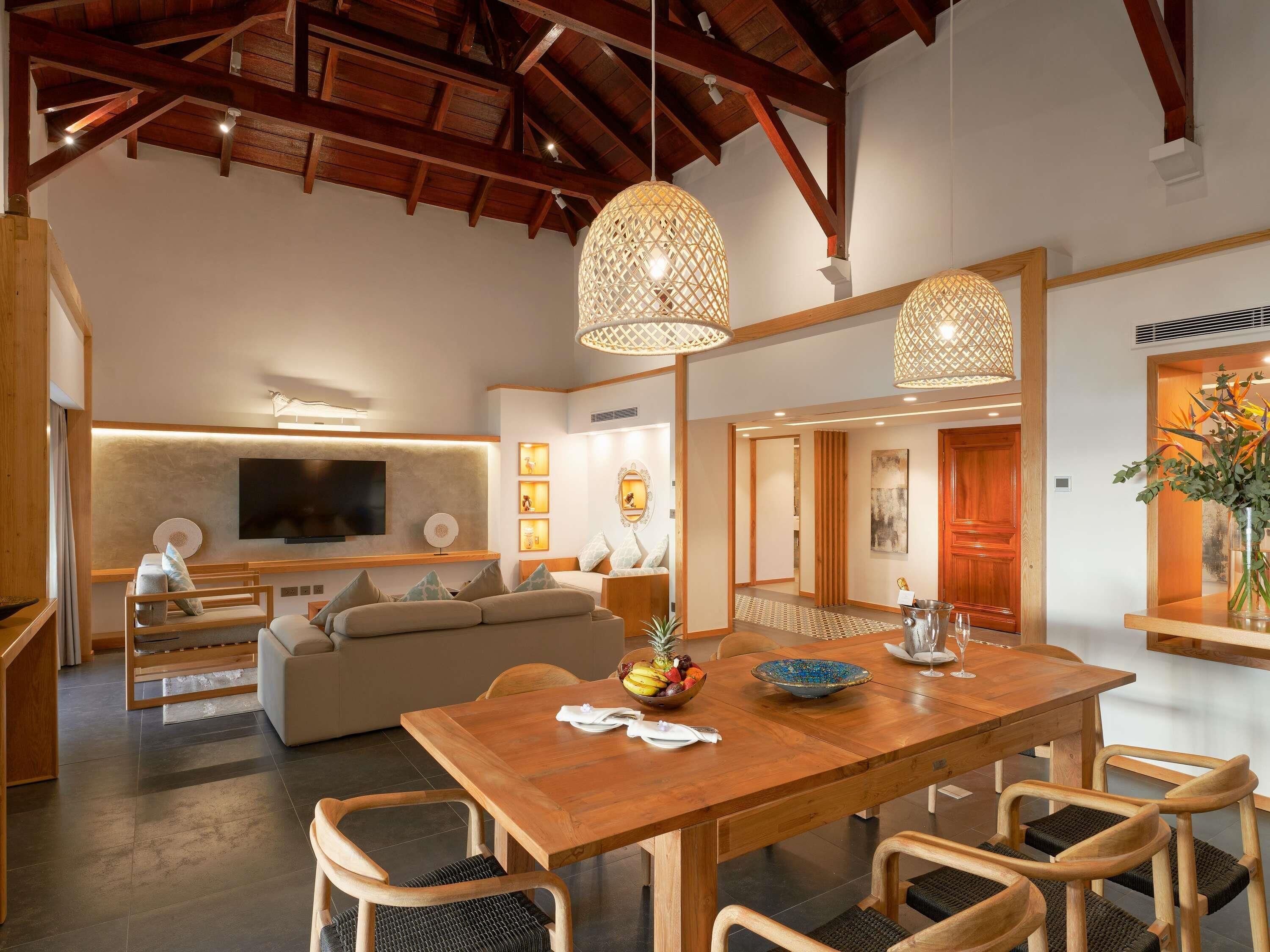 Un interno moderno con un tavolo da pranzo in legno, sedie, un divano e una TV fissata al muro.