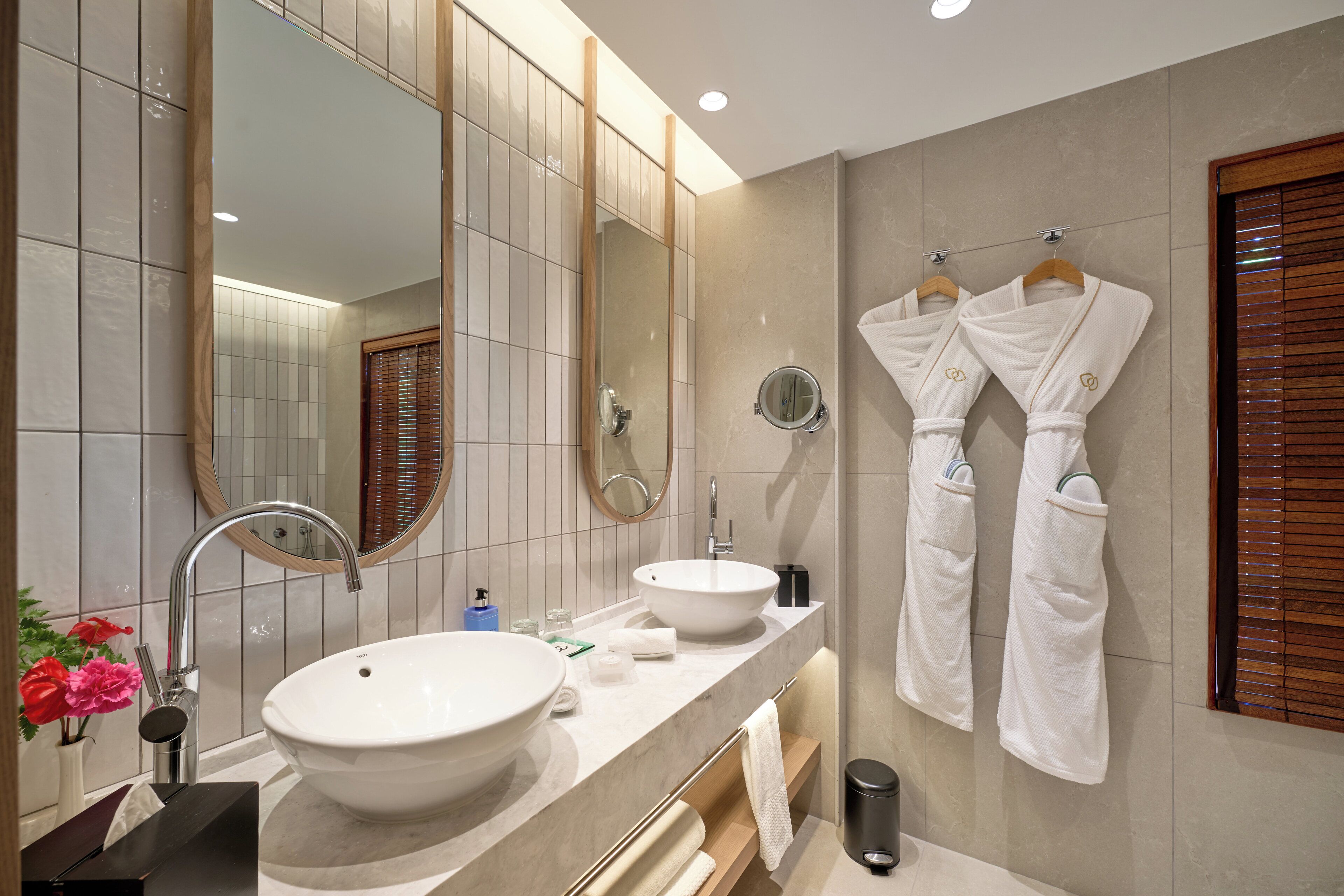 Une salle de bain moderne avec deux lavabos, un grand miroir et des stores en bois.