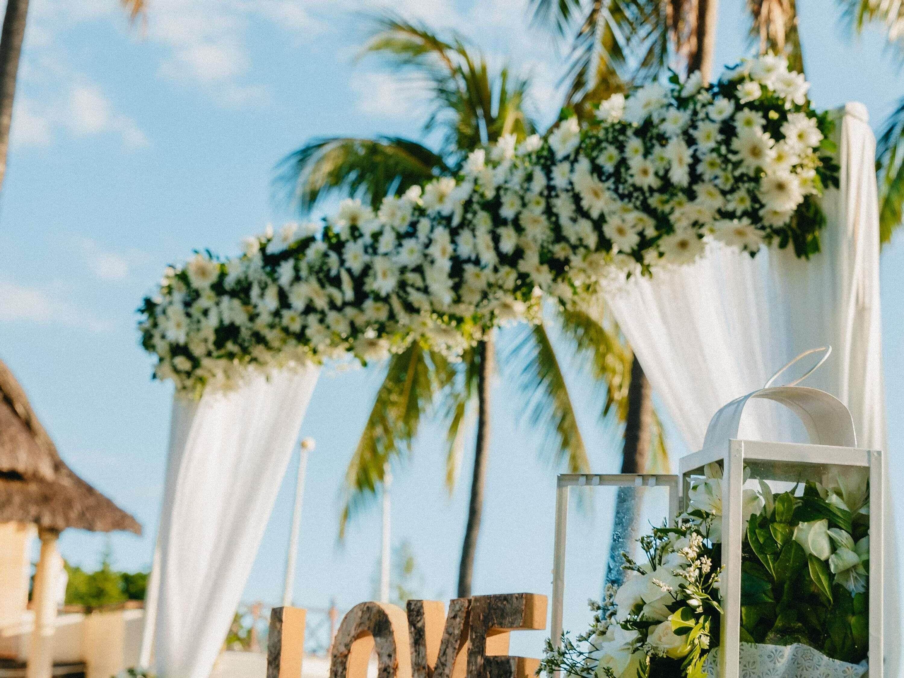 A tropical setting with a floral arch and a large 'LOVE' sign.