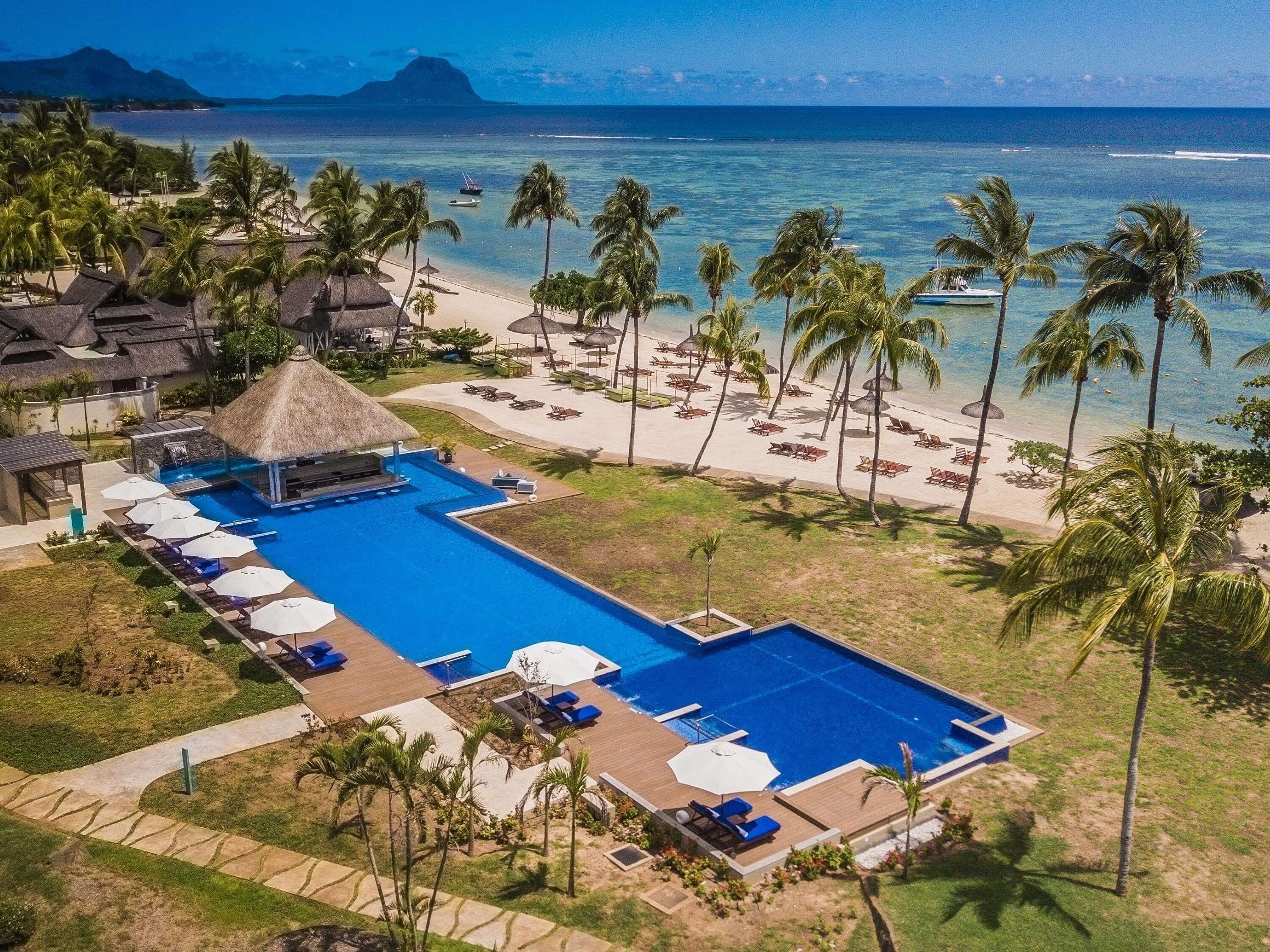 Un complexe hôtelier doté d’une grande piscine, d’une plage et de palmiers.