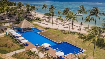 Un complexe hôtelier doté d’une grande piscine, d’une plage et de palmiers.