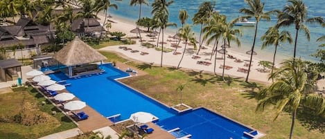 Un complexe hôtelier doté d’une grande piscine, d’une plage et de palmiers.
