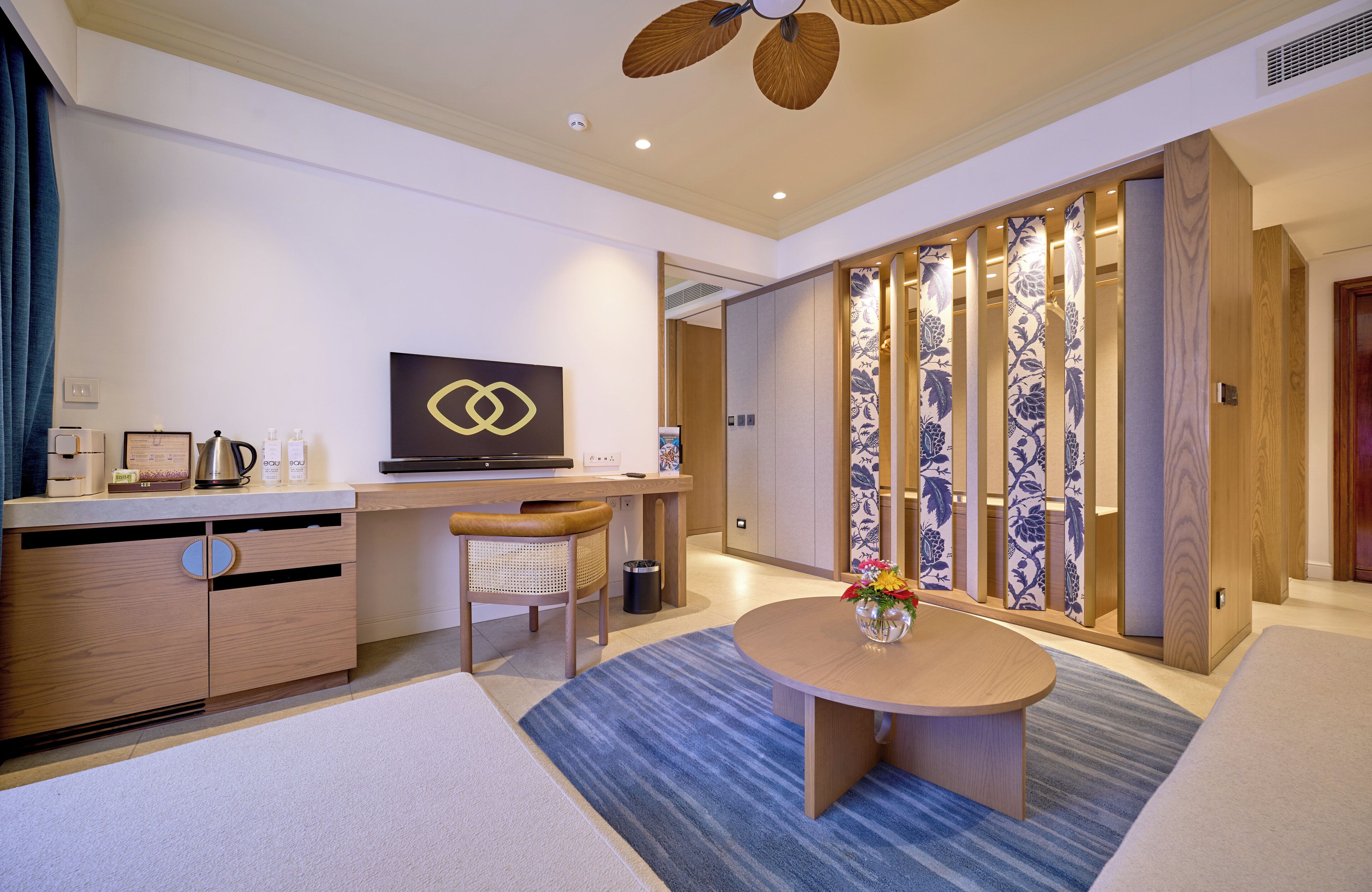 Una camera d'hotel moderna con una scrivania in legno, una televisione, un'area ristoro e una porta scorrevole giapponese tradizionale.
