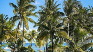 A tropical resort with palm trees, lounge chairs, and a view of the ocean. - Sofitel Mauritius L'Imperial Resort & Spa (Flic-en-Flac)