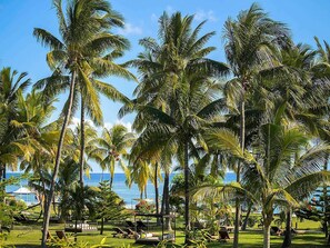 A tropical resort with palm trees, lounge chairs, and a view of the ocean. - Sofitel Mauritius L'Imperial Resort & Spa (Flic-en-Flac)