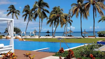 Una piscina al aire libre, sombrillas, sillones reclinables de piscina