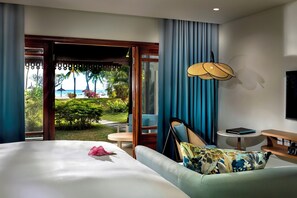 A hotel room with a bed, a desk, a chair, and a view of a garden and beach. - Sofitel Mauritius L'Imperial Resort & Spa (Flic-en-Flac)