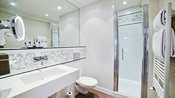 Un baño moderno con lavamanos blanco, inodoro y ducha con mampara de vidrio.