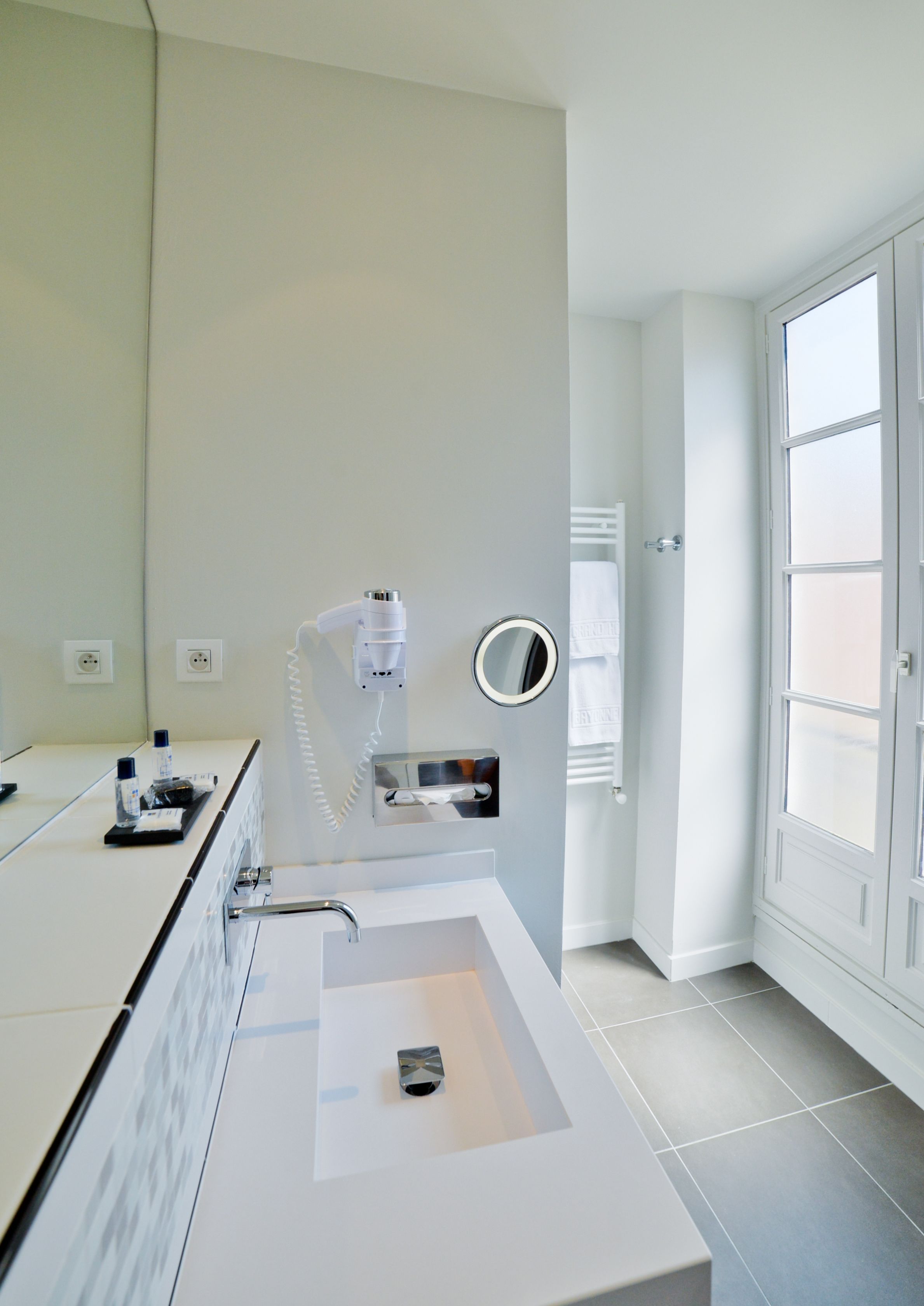 A modern bathroom with a large sink, a hairdryer, and a mirror.