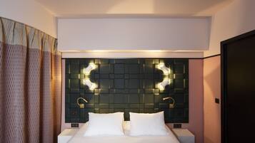 Una habitación de hotel moderna con una cama grande, dos mesitas de noche y un panel decorativo sobre la cama.