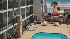 A hotel with a pool, outdoor seating, and a view of the beach. - Wingate by Wyndham Galveston Beachfront at the Seawall (Galveston)