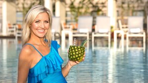 A person holding a pineapple drink by a poolside with lounge chairs and a building in the background. - The St. Anthony, A Luxury Collection Hotel, San Antonio (San Antonio)
