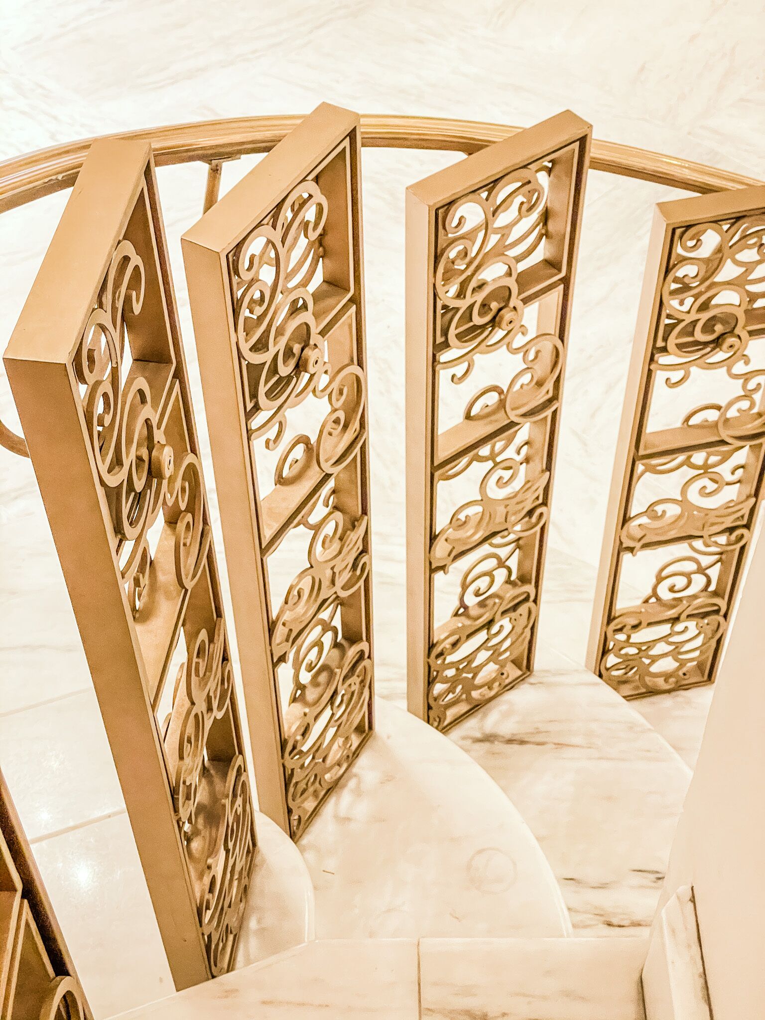 Una escalera de caracol con barandilla dorada y detalles ornamentales.