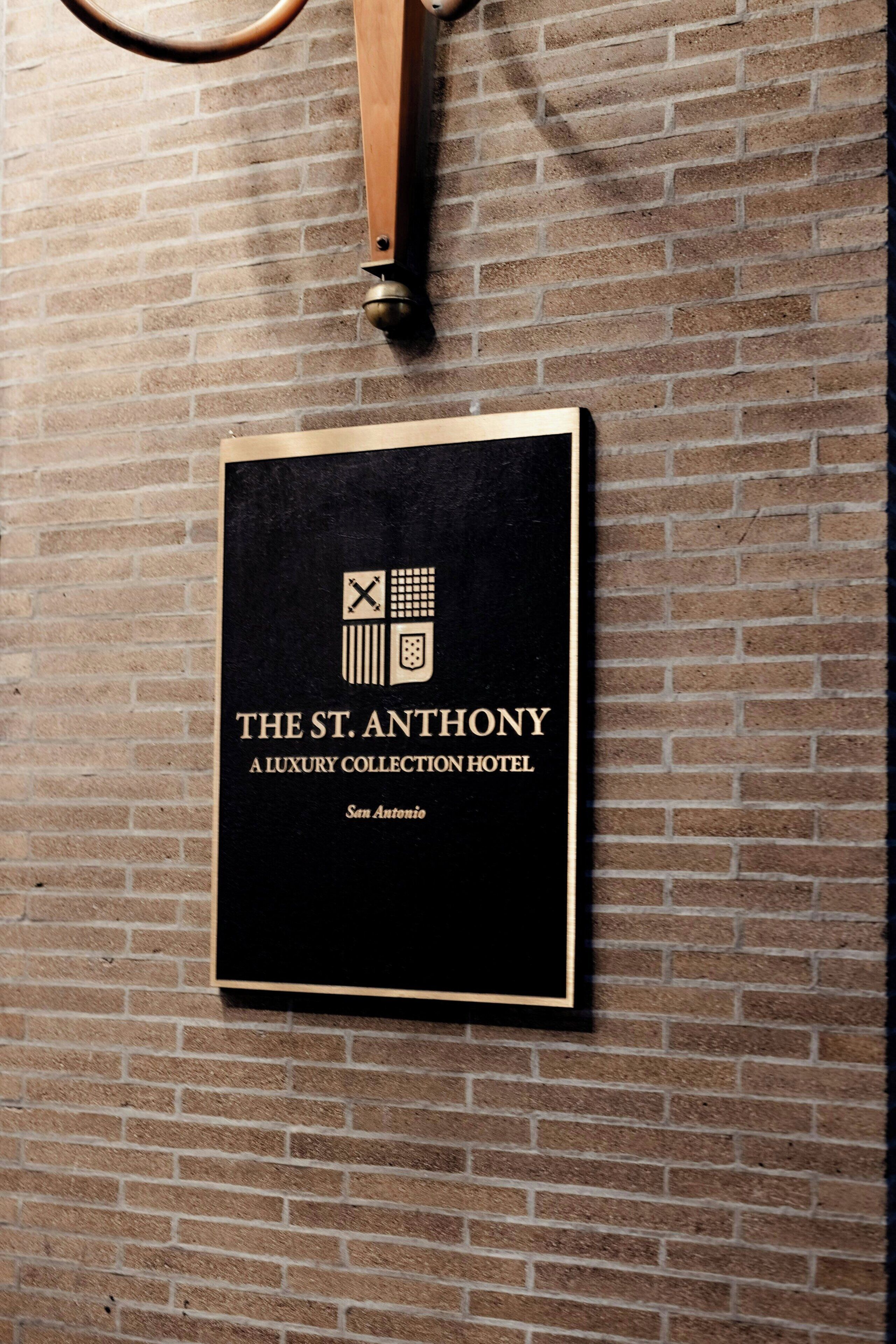 Ein gerahmtes Schild mit der Aufschrift "The St. Anthony A Luxury Collection Hotel" an einer Backsteinmauer.