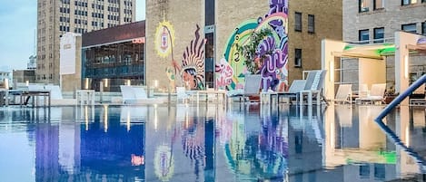 A swimming pool with a reflection of colorful murals on the adjacent building.