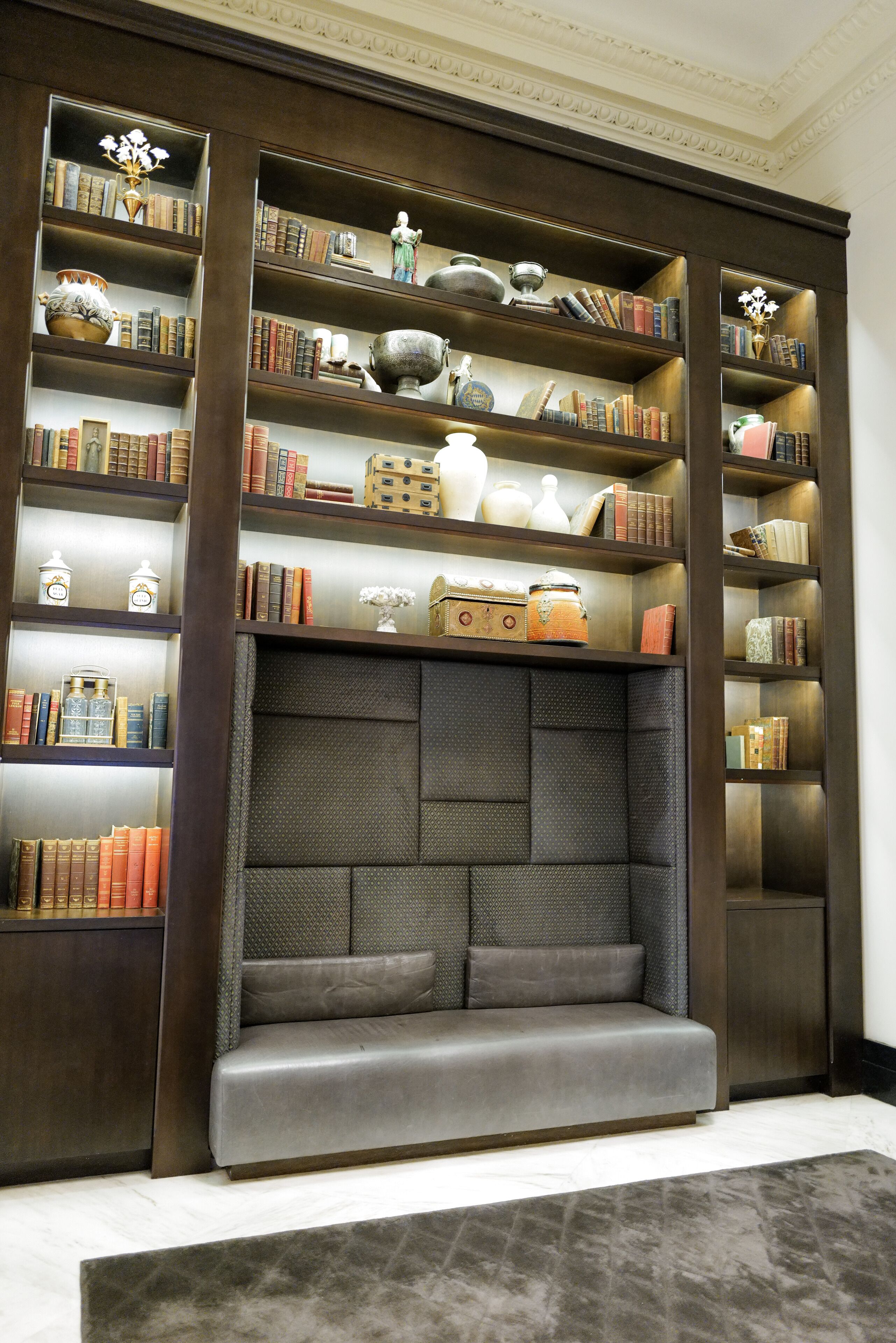 Een bibliotheek met boekenkasten, een zithoek en decoratieve objecten.