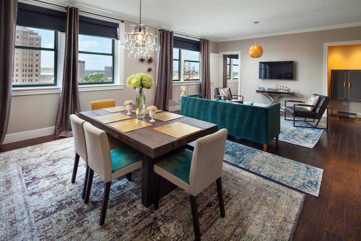 A modern dining area with a wooden table, chairs, and a vase of flowers.