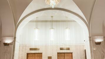 Eine geräumige Lobby mit hoher Decke, einem großen Kronleuchter und zwei Aufzügen.