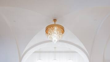 A spacious lobby with marble flooring, two elevators, and a chandelier.