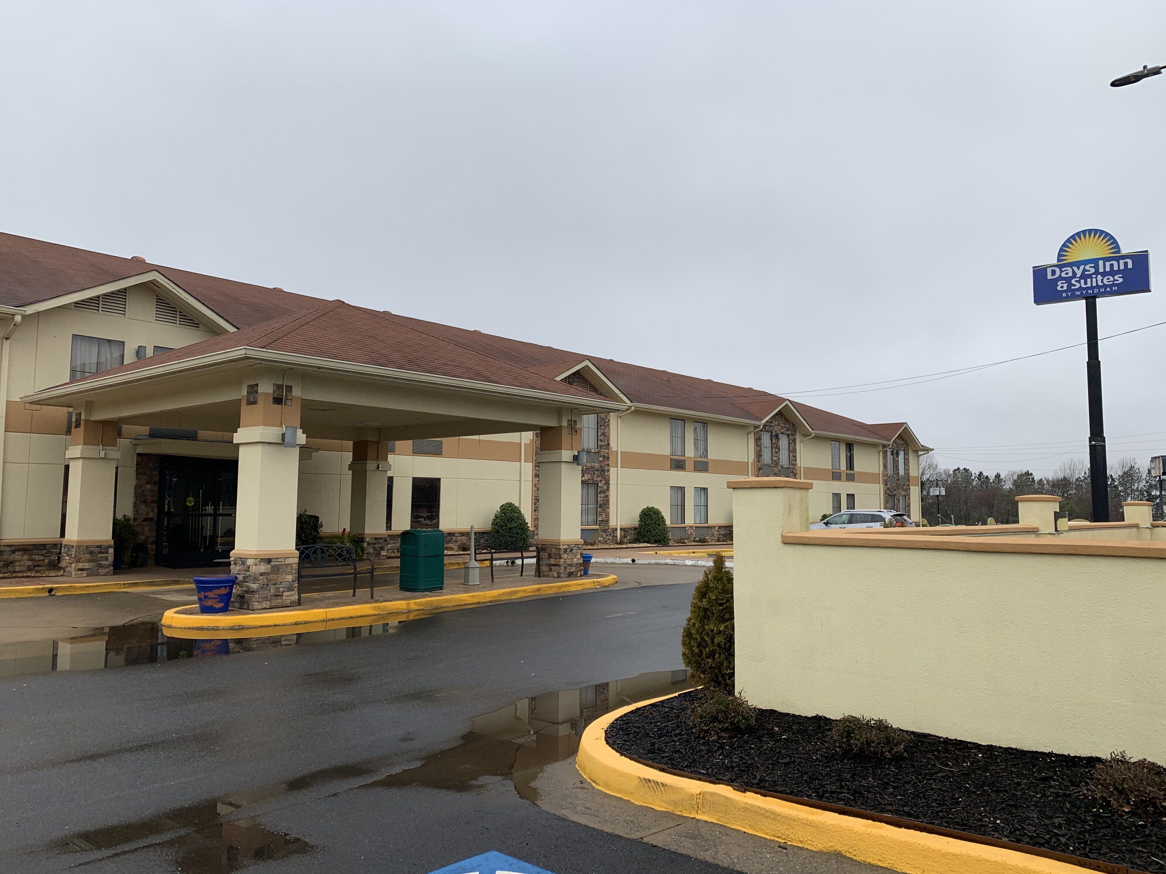 A Days Inn & Suites building with a covered entrance, outdoor trash bins, and a parking lot.