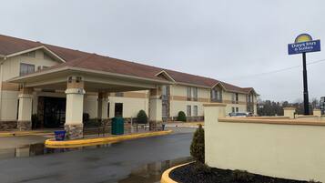 A Days Inn & Suites building with a covered entrance, outdoor trash bins, and a parking lot.