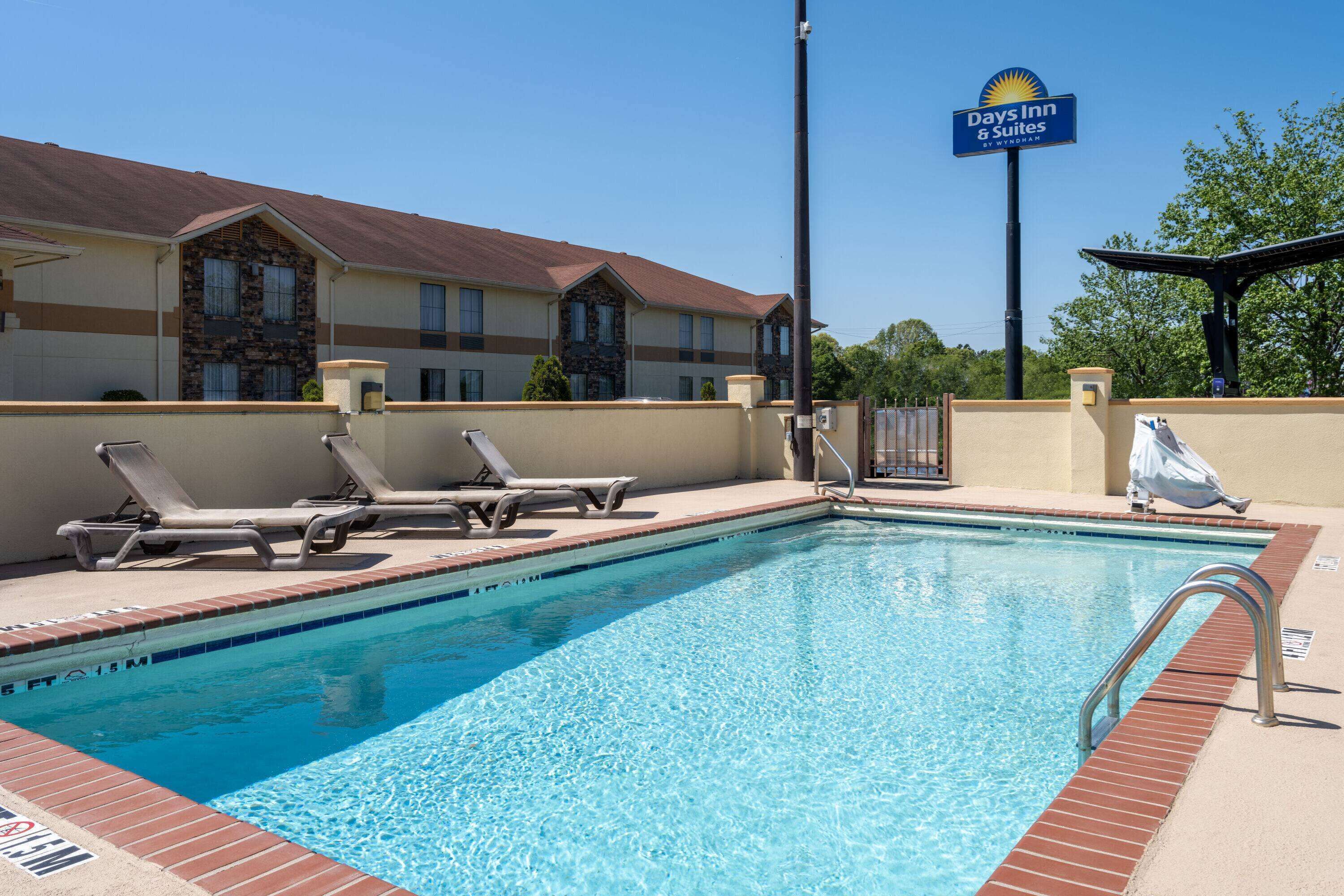 A swimming pool with lounge chairs and a Days Inn sign.