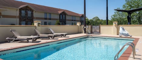 A swimming pool with lounge chairs and a Days Inn sign.