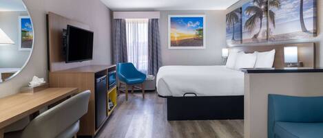 A hotel room with a bed, a desk, a chair, a TV, and a painting of a beach scene.