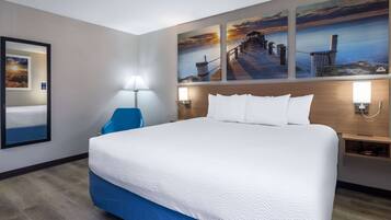 Habitación de hotel con una cama grande, un escritorio y una silla. Hay tres cuadros en la pared sobre la cama.