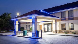 A hotel entrance with a covered outdoor area, a clear sign indicating "Clearance 8'6", and a well-lit facade. - Days Inn & Suites by Wyndham Commerce (Commerce)