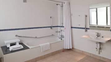 Un baño con bañera, ducha, lavabo y barra de apoyo.